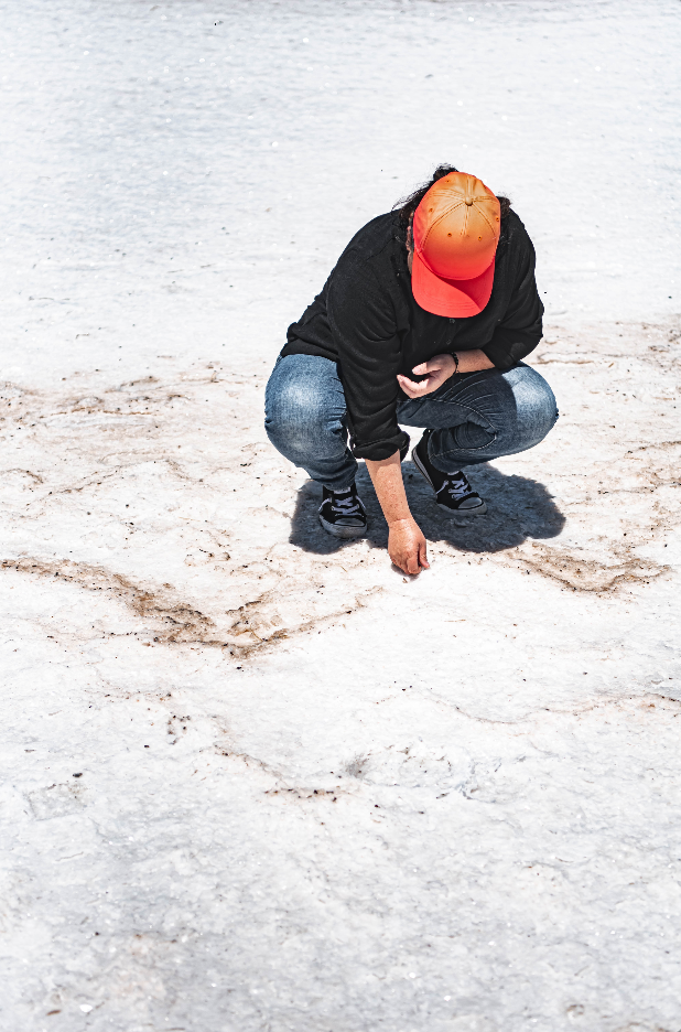 a person in an orange hat crouches on the solid salt of lake dumbleyung